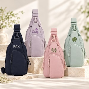 May include: Four sling backpacks in navy, lavender, dusty pink, and sage green. Each bag features a single adjustable shoulder strap, a front zippered pocket, and custom embroidery: R&K, Daisy with a flower, Margaret, and a four-leaf clover.