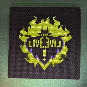 May include: Cross-stitch embroidery of a yellow flame design with a purple heart in the centre. The heart has the text "LONG LIVE" inside.