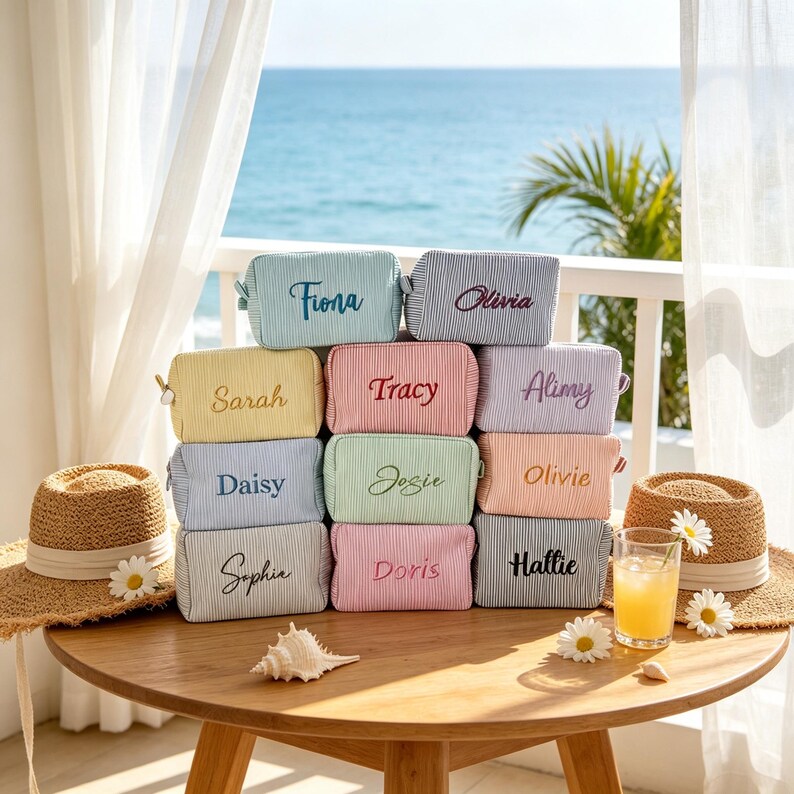 May include: A collection of ten rectangular zipped pouches in various pastel colours, each featuring a fine pinstripe pattern and a unique name embroidered in cursive script, including Fiona, Olivia, Sarah, Tracy, Alimy, Daisy, Josie, Olivie, Sophia, Doris, and Hattie.