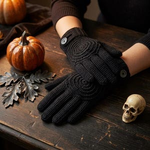 May include: A pair of black crochet gloves featuring a circular pattern on the back of the hand and a single button closure at the wrist. The gloves are constructed with a dense, textured knit stitch and cover the fingers and palms completely.