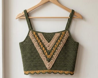 May include: A sleeveless crochet crop top in olive green, featuring a V-shaped panel on the front with alternating stripes of beige and mustard yellow yarn. The garment has a square neckline, two shoulder straps, and a scalloped bottom hem.