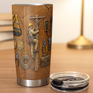 May include: A stainless steel tumbler with a tan, cracked-earth background featuring a graphic of a utility worker climbing a wooden pole. The design includes tools, a safety harness, gloves, a coil of rope, and the name DAVID in yellow text.