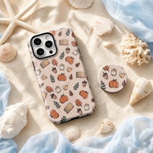 Op de afbeelding: Een lichtbeige smartphonehoesje en een bijpassende ronde telefoonhouder met een herhalend patroon van oranje pompoenen, bruine eikels, open boeken, brandende kaarsen, koffiemokken en groene takjes met bladeren.