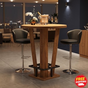 May include: A round wooden bar table with a central pedestal base and a black metal footrest, accompanied by two black upholstered bar stools with silver metal stems and circular bases. A metal ice bucket and two glasses sit on top.