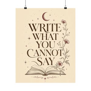 May include: A cream-colored wall art print featuring the dark brown text WRITE WHAT YOU CANNOT SAY above an open book illustration. A crescent moon, stars, and a delicate vine with flowers extend from the book, all rendered in a fine-line style.