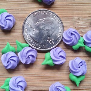 K&ouml;nnte beinhalten: Nahaufnahme einer Gruppe von lila und gr&uuml;nen Zuckerblumen-Dekorationen. Die Blumen sind etwa so gro&szlig; wie eine US-amerikanische 25-Cent-M&uuml;nze.