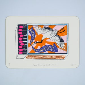 May include: A rectangular print featuring a matchbox design with a crane illustration. The matchbox has pink match heads, and the design includes the text "MADE IN JAPAN" and "BEST MATCH" on a blue banner, set against an orange and pink background.