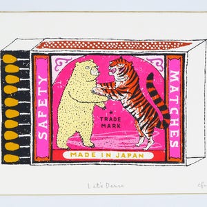 Peut inclure: Impression rectangulaire représentant une boîte d'allumettes avec un ours et un tigre dansant. La boîte d'allumettes a des accents roses et rouges, avec les mots "SAFETY MATCHES" et "MADE IN JAPAN". La phrase "Let's Dance" est écrite en bas.