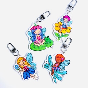 May include: Four acrylic keychains featuring colourful fairy illustrations. One shows a fairy with blue hair on a lily pad with a frog, another a fairy on a yellow flower, one with blonde hair holding a blue flower, and one riding a blue dragonfly.