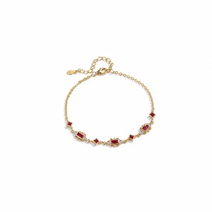 May include: A gold chain bracelet featuring a series of rectangular and square red gemstones interspersed with small clear stones. The bracelet includes a delicate link chain, a lobster claw clasp, and an adjustable extender chain with a small charm.