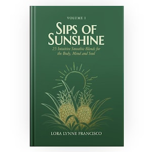 May include: A dark green hardcover book titled Sips of Sunshine, Volume 1, 25 Intuitive Smoothie Blends for the Body, Mind and Soul by Lora Lynne Francisco. The cover features a gold line art illustration of two pineapples and a sun.