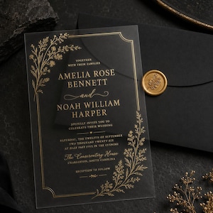 May include: A rectangular clear acrylic wedding invitation featuring gold foil floral illustrations and gold text. The invitation displays the names Amelia Rose Bennett and Noah William Harper, with a gold wax seal on a black envelope nearby.