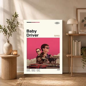 May include: A vertical rectangular movie poster for Baby Driver with a cream background and a large pink central panel. The poster features a red car, a group of actors, and the text Baby Driver, Directed by: Edgar Wright, and /17.