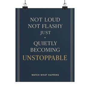 May include: A dark blue rectangular wall poster featuring the white text NOT LOUD NOT FLASHY JUST QUIETLY BECOMING UNSTOPPABLE with the word UNSTOPPABLE in gold. The bottom includes the white text WATCH WHAT HAPPENS, framed by thin white vertical lines.