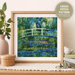 Op de afbeelding: Een kruissteekpatroon als PDF-download met een vierkante afbeelding van een witte boogbrug over een vijver met groen gebladerte en blauw water. Het kunstwerk zit in een lichthouten lijst met een ronde badge met de tekst CROSS STITCH PATTERN.