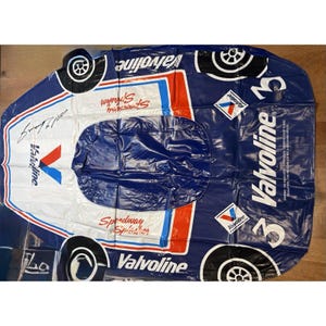 May include: An inflatable pool float shaped like a race car, featuring a dark blue and white color scheme with red accents. It displays the Valvoline logo, the number 3, and the text Speedway Splasher. The design includes black and white wheels.