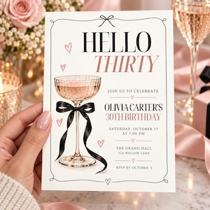 May include: A white rectangular birthday invitation card featuring a black bow at the top, a champagne coupe glass with a black ribbon, and pink hearts. The text reads: HELLO THIRTY, JOIN US TO CELEBRATE, OLIVIA CARTER'S 30TH BIRTHDAY, SATURDAY, OCTOBER 17 AT 7:00 PM, THE GRAND HALL 123 WILLOW LANE, RSVP BY OCTOBER 5.