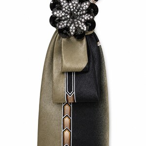 May include: A necktie featuring a split design of metallic gold and black fabric. The center displays a vertical stripe with a repeating geometric arrow pattern in bronze, white, and black. A large, dark floral brooch with clear crystals is attached.