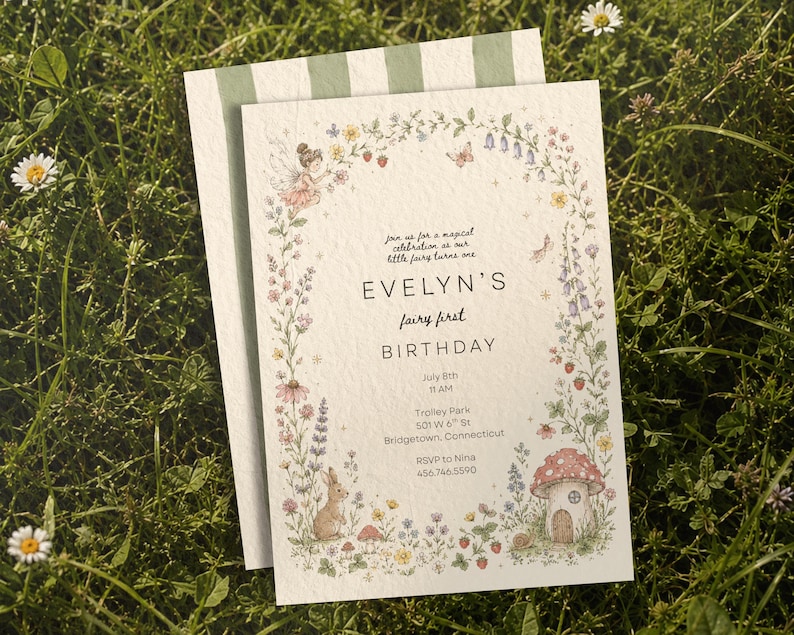 May include: A white rectangular birthday invitation card featuring a floral border with a fairy, a rabbit, and a mushroom house. The text reads: Join us for a magical celebration as our little fairy turns one, EVELYN'S fairy first BIRTHDAY, July 8th, 11 AM, Trolley Park, 501 W 6th St, Bridgetown, Connecticut, RSVP to Nina, 456.746.5590.
