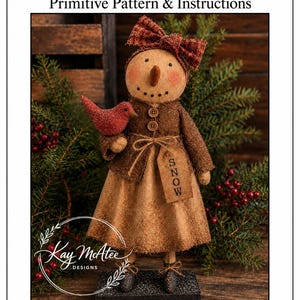 May include: A fabric snowman doll with a tan face, orange carrot nose, and rosy cheeks, wearing a brown jacket with two buttons, a matching skirt, and a plaid bow. It holds a red bird and a tag labeled SNOW. The doll stands 22 inches tall.