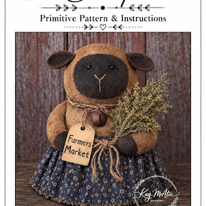 Puede incluir: Una muñeca de oveja de tela marrón y negra con una falda azul marino con estampado floral. La oveja sostiene un manojo de hierbas secas y una etiqueta beige con la inscripción Farmers Market. Una campana marrón cuelga de su cuello. El texto dice Farm Friend Sheep Primitive Pattern & Instructions 35,56 cm de alto.
