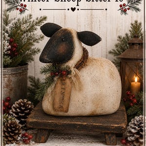 May include: A sheep figurine with a cream-coloured body and a dark brown face, featuring a small tag labelled WINTER, a twig wreath, and a sprig of greenery around its neck. The sheep sits on a small, dark wooden stool, measuring 25.4 cm in height.