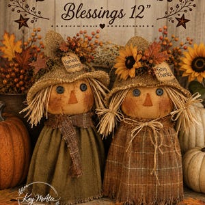 May include: Two 12-inch scarecrow dolls with burlap hats, button eyes, and straw hair. One wears a solid olive green dress with a scarf, the other a brown plaid dress. Both feature autumn floral accents and tags reading Harvest Blessings and Give Thanks.