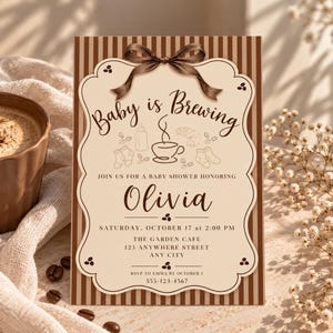 Può includere: Un biglietto d'invito rettangolare per baby shower con sfondo a righe verticali marroni e crema. Il centro presenta una cornice smerlata color crema con un fiocco di nastro marrone in alto. Il testo recita: Baby is Brewing, Olivia, Saturday, October 17 at 2:00 PM, The Garden Cafe, 123 Anywhere Street, Any City, RSVP to Emma by October 1, 555-123-4567. Le grafiche includono un biberon, una tazza di caffè, un croissant, calzini e chicchi di caffè.