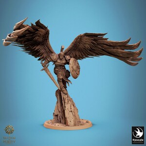 Könnte beinhalten: Eine braune, unbemalte Miniaturfigur eines geflügelten Kriegers auf einem felsigen Sockel. Die Figur trägt eine Rüstung, einen Helm und hält ein Schwert in der einen und einen runden Schild in der anderen Hand. Große, detaillierte Flügel sind ausgebreitet.