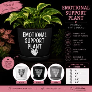 May include: A black plant pot with a matching saucer containing a green and yellow variegated plant. The pot features the white text "EMOTIONAL SUPPORT PLANT" and a leaf icon. Additional white, black, and gray pots are shown with the same text.
