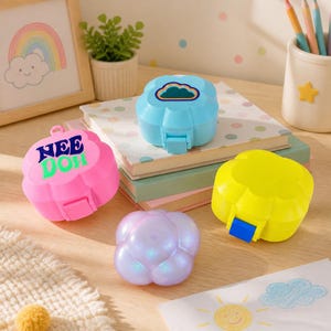 May include: Three small, flower-shaped plastic containers in bright pink, neon yellow, and iridescent purple, plus one light blue container with a cloud graphic. The pink container features the text NEE DOH in bold, dark blue and green letters.
