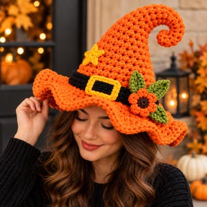 Peut inclure: Un chapeau de sorcière crocheté orange vif avec une bande noire dotée d'une boucle jaune, une petite étoile jaune décorative et un groupe de feuilles vertes avec une fleur orange fixé sur le côté du large bord ondulé.