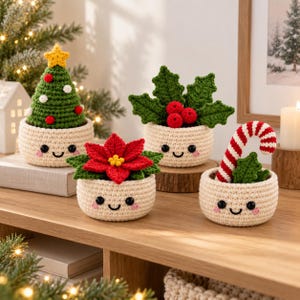 Peut inclure: Quatre petits pots crochetés de couleur crème, ronds, avec des visages souriants, des joues roses et des yeux noirs. Ils contiennent un sapin de Noël vert avec une étoile jaune, du houx vert à baies rouges, un poinsettia rouge et un sucre d'orge.