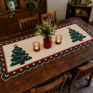 May include: A rectangular crochet table runner featuring a cream-colored center with two green Christmas tree motifs decorated with gold stars and red ornaments. The runner has a scalloped border in red, green, and gold with white beads.
