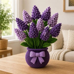 May include: A crochet flower arrangement featuring multiple shades of purple hyacinth-like blooms with green leaves, housed in a round, deep purple textured crochet pot decorated with a matching purple crochet bow on the front center.