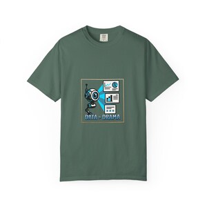 Könnte beinhalten: Ein dunkel salbeigrünes T-Shirt mit einer Grafik eines kleinen Roboters, der blaues Licht auf drei Datendiagramme projiziert. Unter dem Roboter ist der Text "DATA > DRAMA" in blauen Buchstaben gedruckt. Das Design ist von einem dünnen, hellen Quadrat umrahmt.