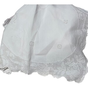 May include: White cotton tablecloth with a crocheted lace border and embroidered square designs.