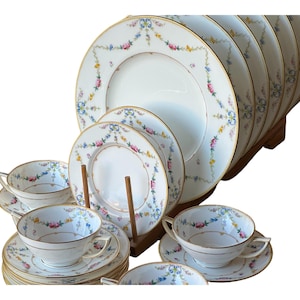 May include: A vintage floral china dinner service with a gold trim. The set includes plates, saucers, and cups.