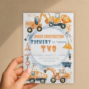 May include: A rectangular birthday invitation card featuring watercolour construction vehicles, a traffic cone, a hard hat, and a wheelbarrow. The text reads: UNDER CONSTRUCTION ZACHARY IS TURNING TWO, Saturday | January 1st | 1:00PM, RSVP by December 20th, 0400 000 000.