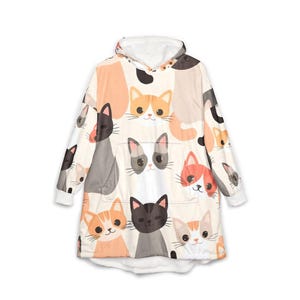 Può includere: Una felpa con cappuccio oversize caratterizzata da un motivo ripetuto di volti di gatti in stile cartoon in vari colori, tra cui arancione, nero, grigio e bianco. Il capo presenta maniche lunghe, una grande tasca a marsupio e un cappuccio.