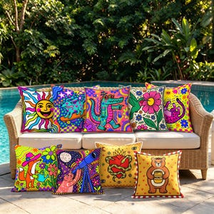 May include: A collection of nine square throw pillows featuring vibrant, colorful graphic illustrations including a smiling sun, a skateboarding dog, a crocodile, a hummingbird, a fox, a cat with a telescope, a heart, and a bear holding honey.