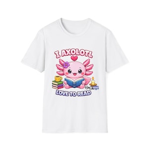May include: A white t-shirt featuring a graphic of a pink axolotl reading a blue book. The design includes a stack of books, a yellow mug, a candle, and glasses, with the text "I AXOLOTL LOVE TO READ" printed in pink and blue lettering.
