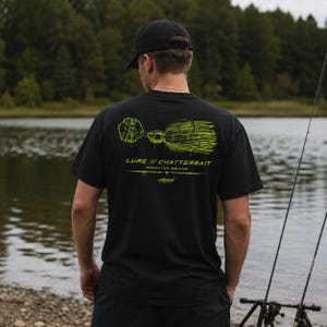 Könnte beinhalten: Ein schwarzes Kurzarm-T-Shirt mit einer neongrünen Grafik eines Angelköders auf der Rückseite. Der Text lautet LURE // CHATTERBAIT PREDATOR SERIES und enthält ein kleines Logo. Das Design ist in einer tropfenden Tintenoptik gedruckt.