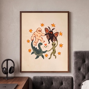 May include: A framed wall art print featuring a cream-colored background with a central illustration of a white yeti, a black moth creature, a green sea monster, and a green alien holding hands in a circle around a small orange flower, surrounded by orange stars.