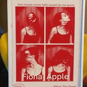 May include: A framed poster featuring four red and white panels showing a person in different poses. The text reads: And maybe some faith would do me good. Fiona Apple, 1999, and When The Pawn.. The print is enclosed in a simple white rectangular frame.
