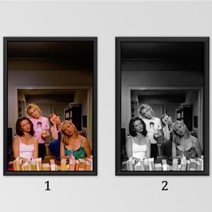 May include: Two framed wall art prints featuring a group of four women in a room. The left print is in full colour, while the right print is in black and white. Both images show the same scene of women posing with books in the foreground.