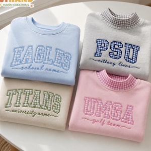 May include: Four sweatshirts featuring embroidered collegiate-style lettering and gingham patterns. The light blue sweatshirt says EAGLES, the beige one says TITANS, the gray one says PSU nittany lions, and the pink one says UMGA golf team.
