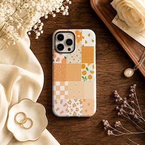 May include: A rectangular smartphone case featuring a multi-panel collage design in various shades of orange, cream, and white. The pattern includes small citrus fruits, gingham checks, checkered squares, floral motifs, and star shapes.