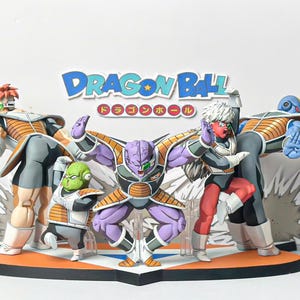 Puede incluir: Un conjunto de figuras de Dragon Ball que muestra a cinco personajes en poses de batalla, vistiendo armaduras naranjas y grises con visores verdes. La base incluye un logotipo y un fondo recortado con el texto Dragon Ball.