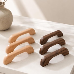 May include: Six wooden cabinet handles arranged in two columns of three. The left column features three light-toned wood handles, while the right column displays three dark-toned wood handles. Each handle has a curved, arch-like shape.